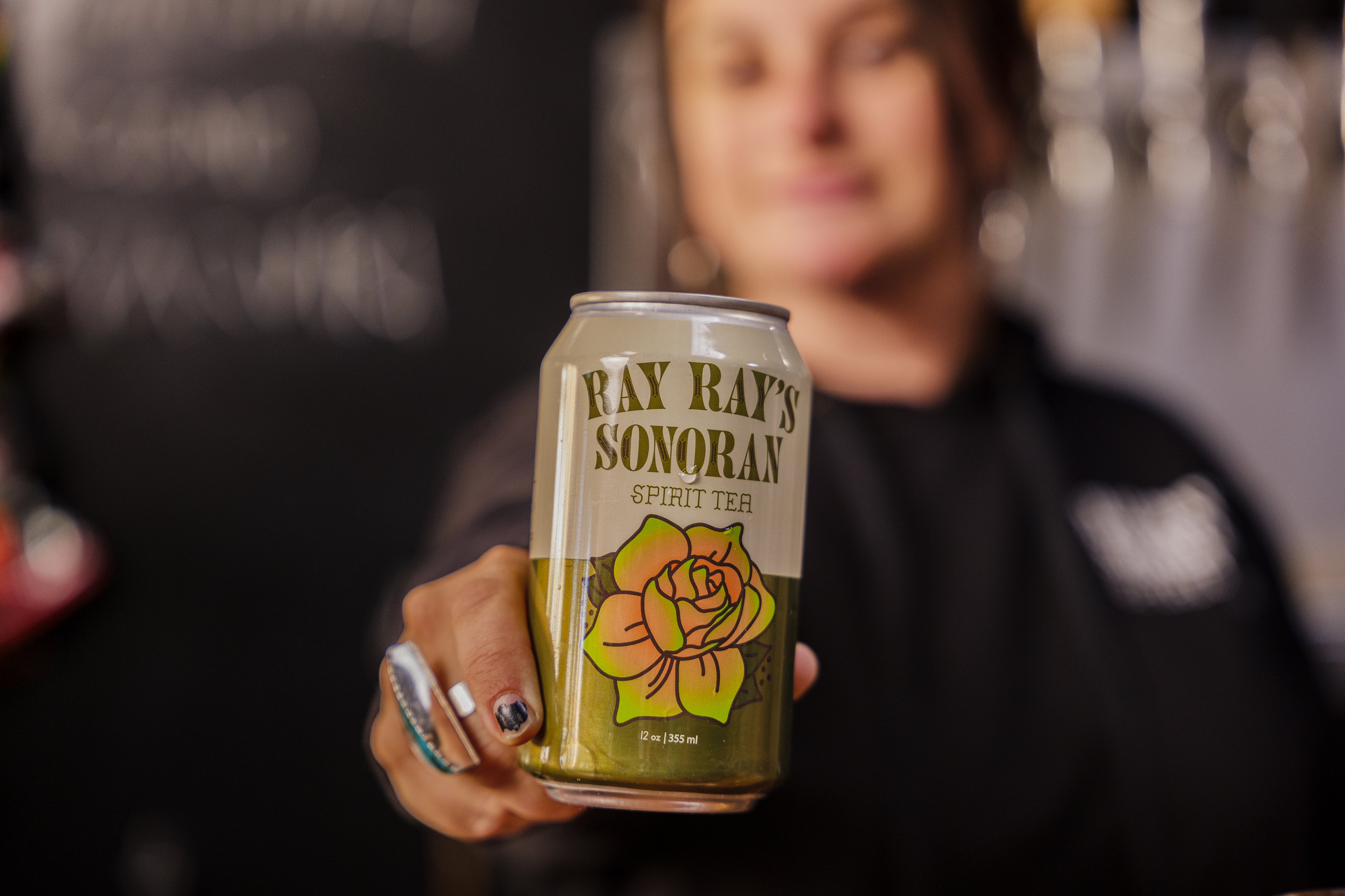 Person holding a can of 'Ray Ray's Sonoran Spirit Tea' with a blurred background